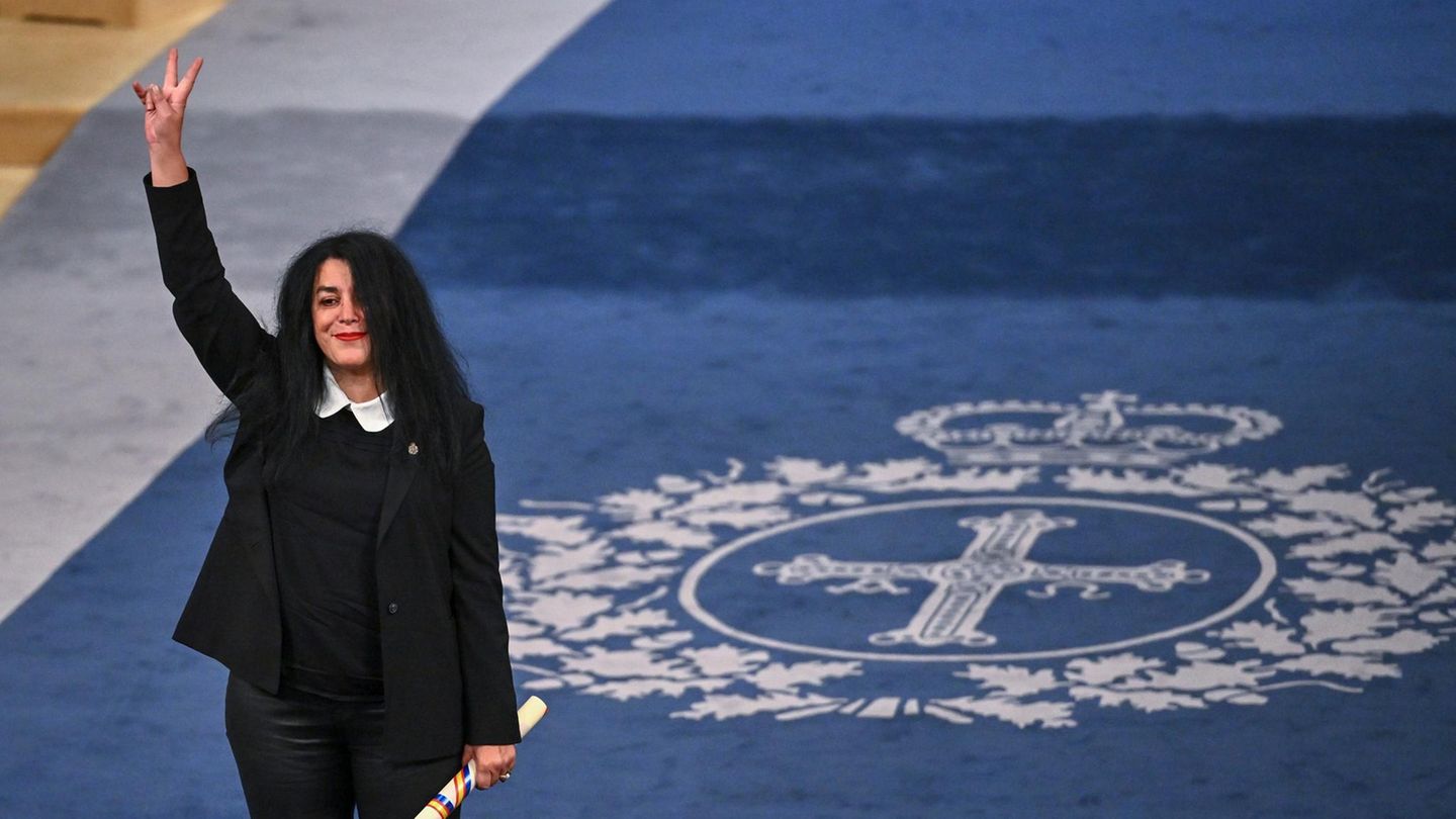 Marjane Satrapi reckt den Arm in die Luft und macht ein Peace-Zeichen