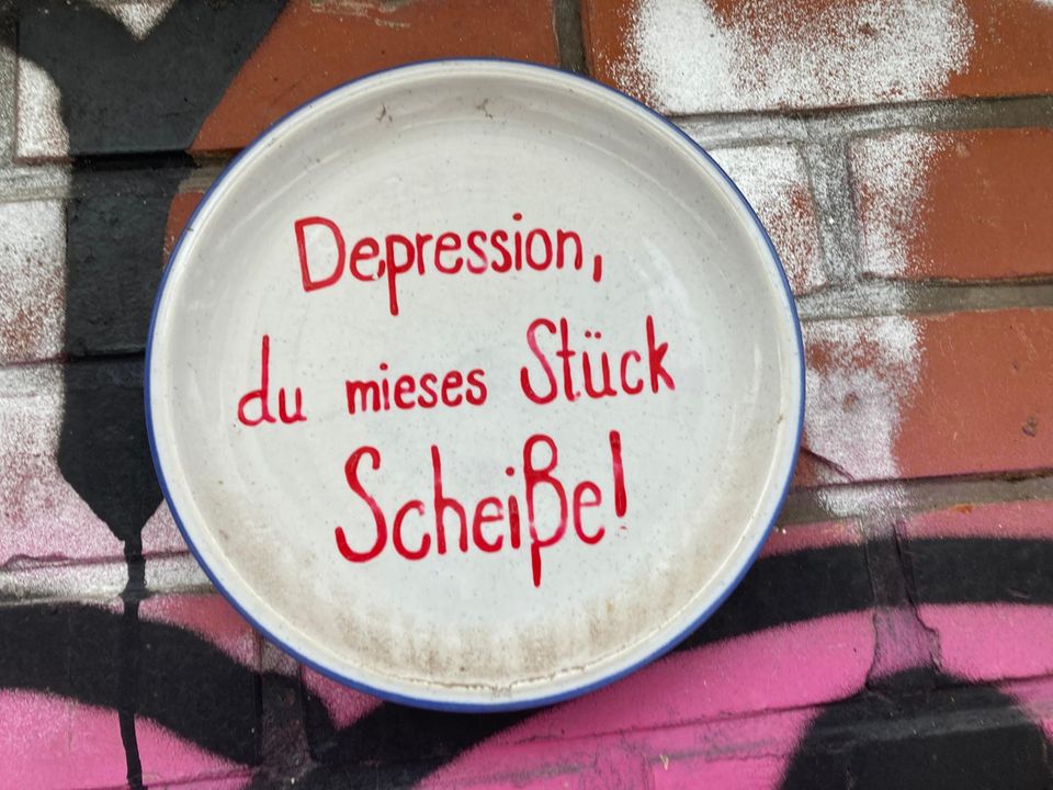 Teller mit aufgemaltem Spruch: Depression, du mieses Stück Scheiße!