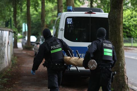 Polizisten tragen einen Rammbock. Foto: Christoph Reichwein/dpa