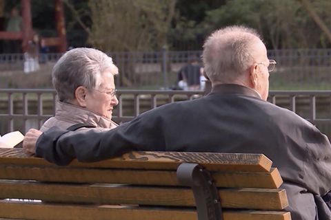 Zwei Rentner sitzen auf einer Parkbank.