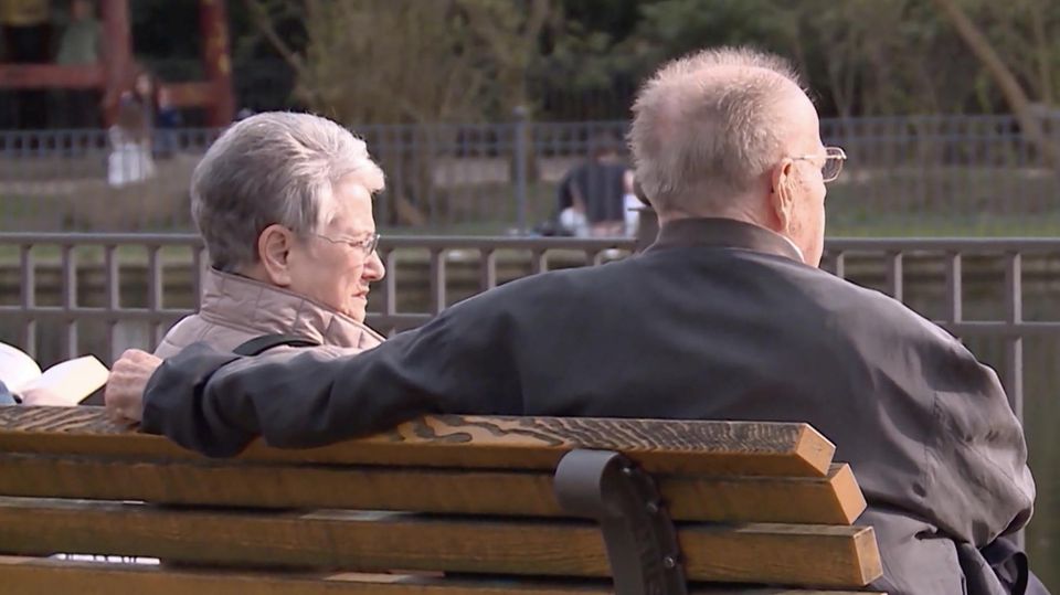 Zwei Rentner sitzen auf einer Parkbank.