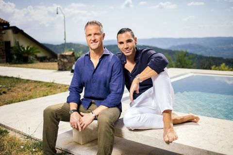 Ralph Schumacher sitzt mit seinem Partner Etienne auf einer Bank an einem Pool