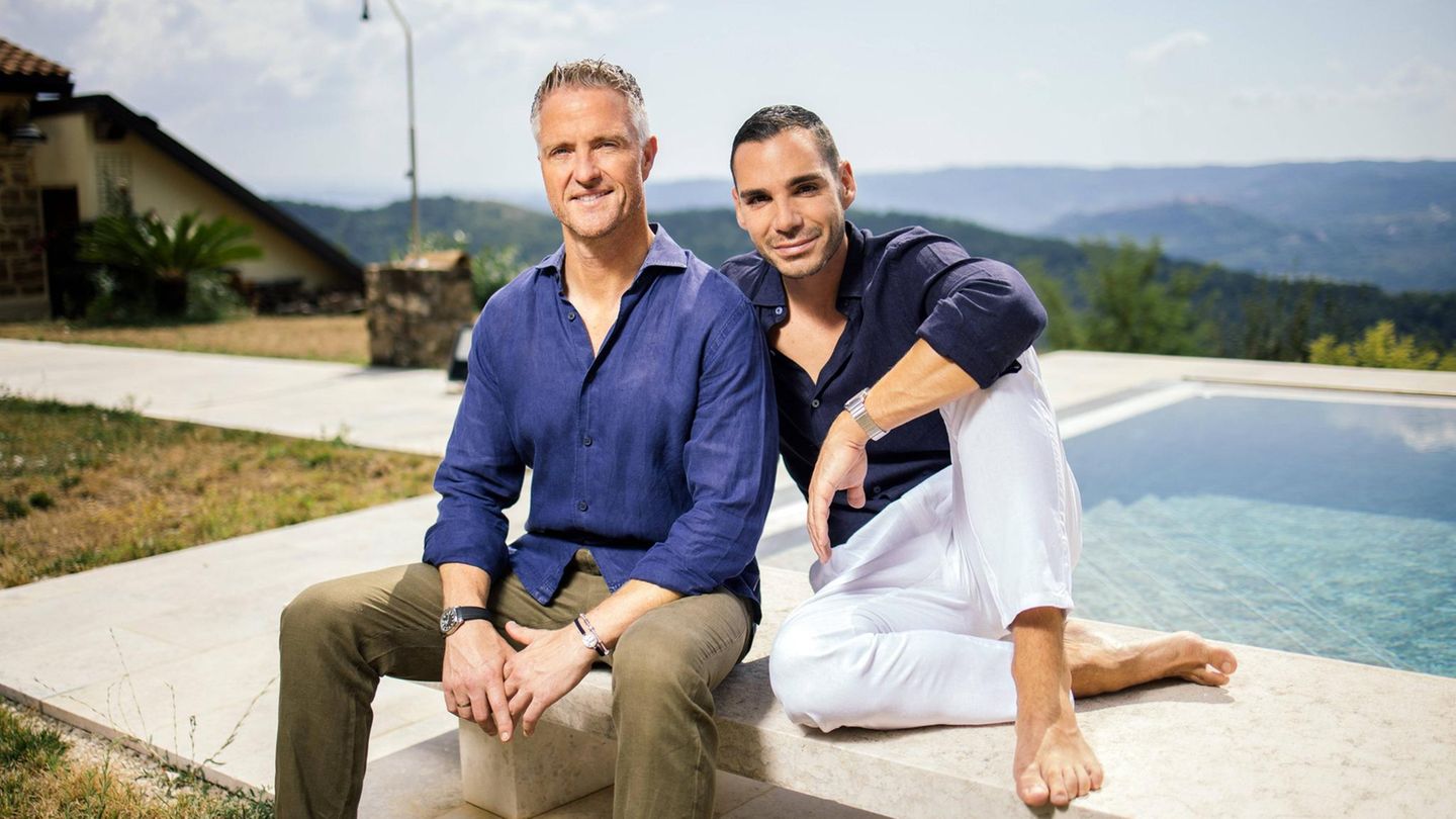 Ralph Schumacher sitzt mit seinem Partner Etienne auf einer Bank an einem Pool