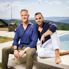 Ralph Schumacher sitzt mit seinem Partner Etienne auf einer Bank an einem Pool