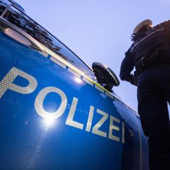 Eine Polizistin steht neben einem Polizeifahrzeug