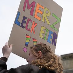 Fall für den Beleidigungsparagrafen? Eine Protestierende hält ein Schild mit der Aufschrift "Merz Leck Eier" in Regenbogenfarben