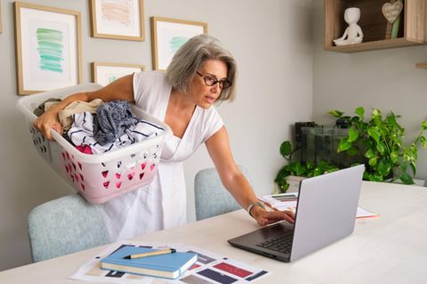 Frau wäscht Wäsche im Homeoffice und begeht Arbeitszeitbetrug