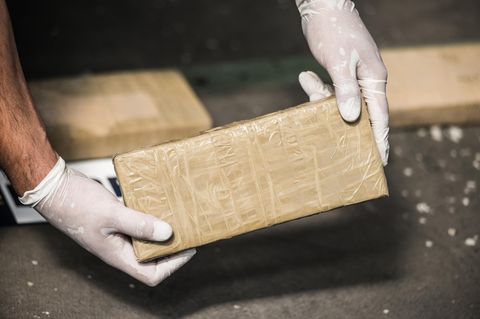 Ein Mann hält ein Drogenpaket in der Hand (Symbolbild)
