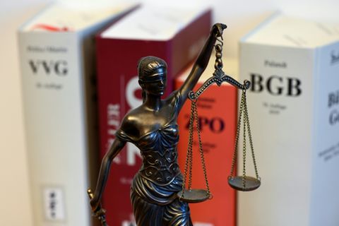 Figur von Justitia vor Gesetzestexten