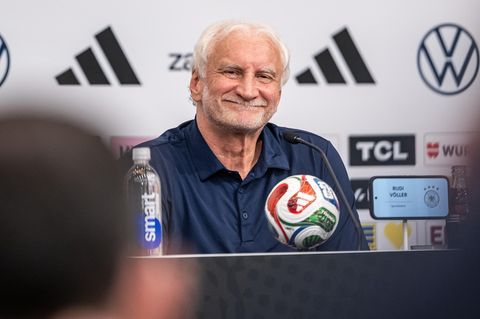 Rudi Völler lächelt auf einer Pressekonferenz im deutschen WM-Quartier