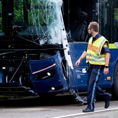 Ein Polizist schaut auf die bei einem Unfall bei München beschädigten Busse