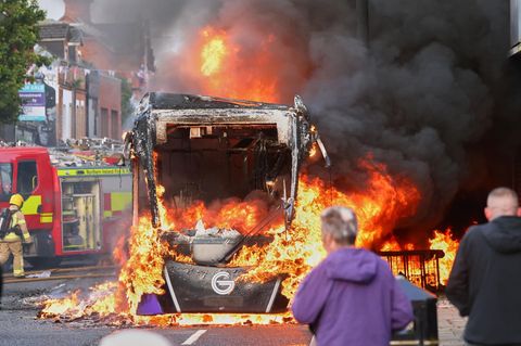 Menschen beobachten, wie ein Fahrzeug während einer Demonstration in East Belfast nach einem Messerangriff in Belfast brennt
