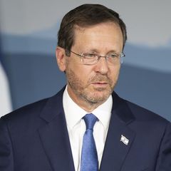 Izchak Herzog, Präsident von Israel, steht im blauen Anzug vor einer Flagge seines Landes
