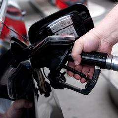 Eine rechte Hand hält eine Zapfpistole in den Tankstutzen eines Autos – Symbolbild Tankrabatt