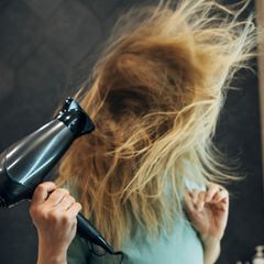 Eine Frau föhnt sich die Haare
