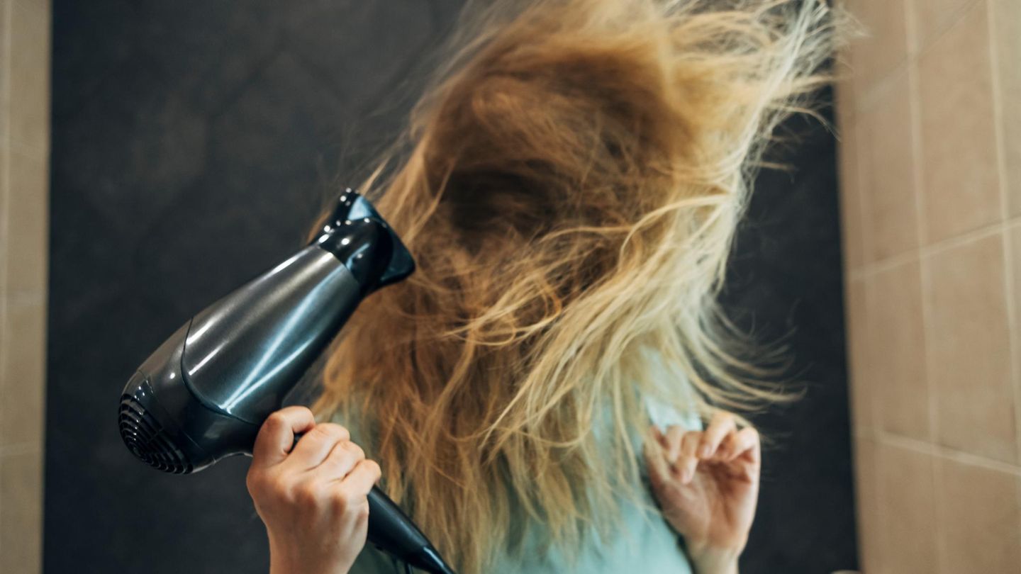 Eine Frau föhnt sich die Haare