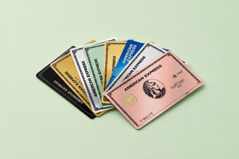 Verschiedene American Express Kreditkarten liegen aufgefächert auf einem hellgrünen Hintergrund.