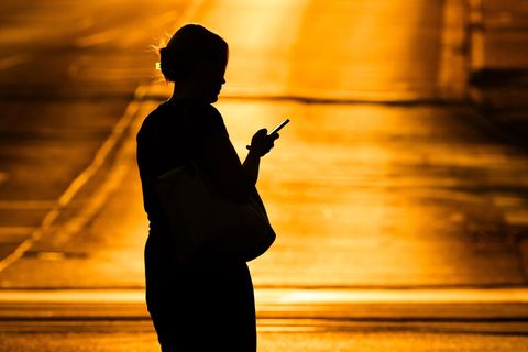 Eine Fußgängerin läuft mit einem Smartphone über eine Straße. In Italien wird dafür eine Strafe fällig.