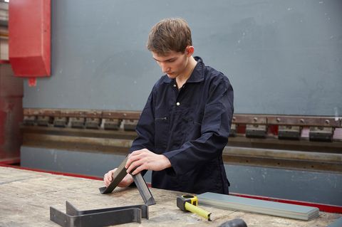 Ein junger Mann steht an einem seinem Tisch in einer Stahlfabrik