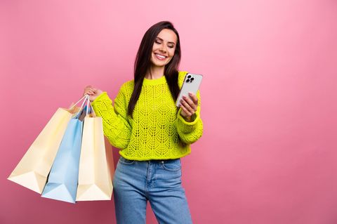 Foto des optimistischen mädchens mit langer frisur gekleidet gelben pullover halten neue otfit schreiben beitrag auf smartphone