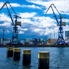Blick vom Wasser auf die TKMS Werft in Mecklenburg-Vorpommern – im Vordergrund zwei Kräne