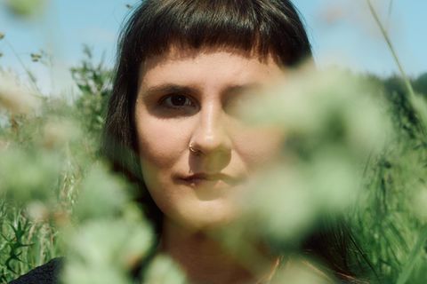 Porträt von Miriam Peters, teilweise verdeckt von Blättern