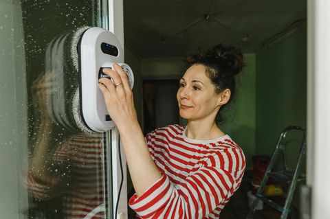 Fensterputzroboter wird von einer Frau bedient.