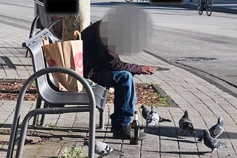 Ein Mann versucht, Tauben anzulocken und einzufangen.