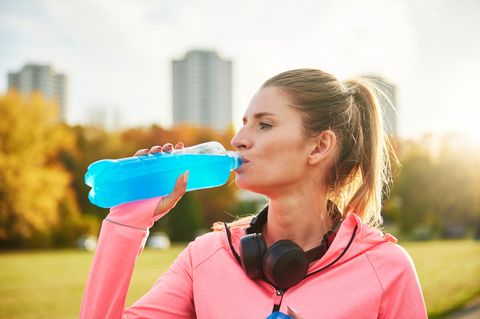 Sportgetränk: Eine Frau trinkt aus einer blauen Flasche