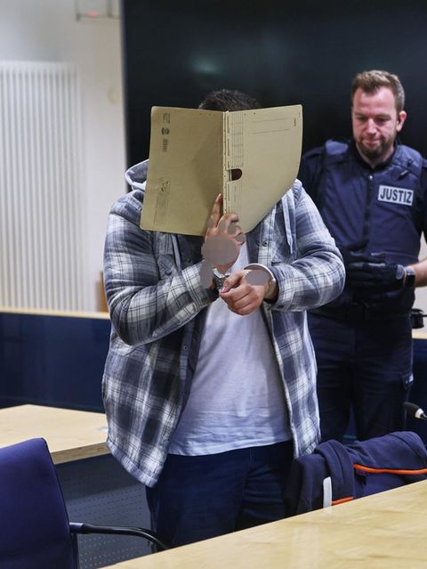 Der Hauptangeklagte Dennis J. aus Soest betritt mit einer Mappe vor dem Gesicht den Saal am Landgericht Arnsberg