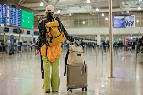 Eine junge Frau steht mit Koffern am Flughafen