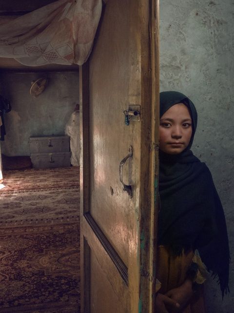 Afghanisches Mädchen versteckt sich. hinter einer Tür