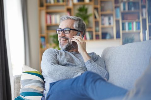 Lächelnder Mann telefoniert auf der Couch.