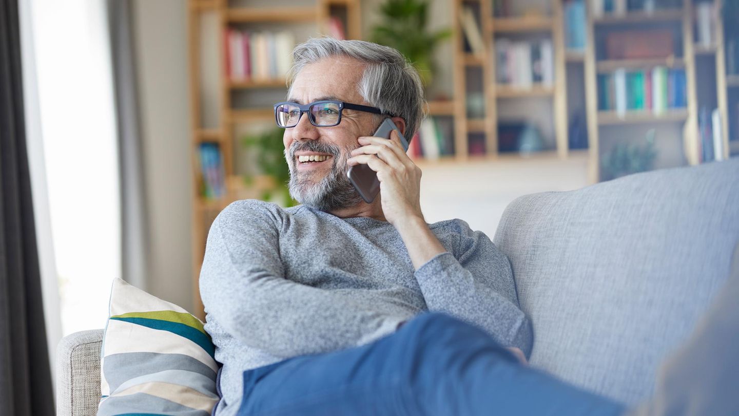 Lächelnder Mann telefoniert auf der Couch.
