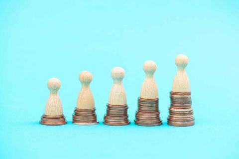 Spielfiguren stehen auf unterschiedlich hohen Münzhaufen