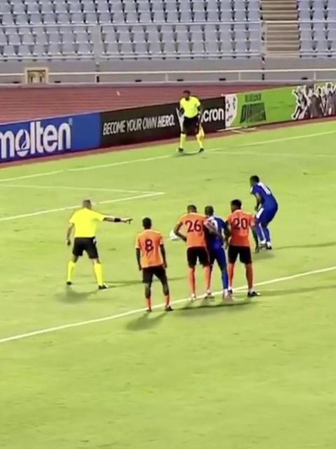 Ein Fußballer in Jamaika läuft langsam zum Ball, um einen Elfmeter zu verwandeln.