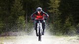 Hier sieht man, warum Funktionskleidung Funktion heißt. Gore Bike Wear ist optisch zurückhaltender als Majola und bietet Fahrradkleidung für Sportler, die aber auch für den alltäglichen Gebrauch geeignet ist.   Die Kleidung stammt aus der ALP-X GT-Reihe. Preisidee: die Jacke kostet etwa 250 Euro. Kaum zu erkennen ist, dass der Biker Überschuhe trägt. Sie halten nicht nur in Wildbächen, sondern auch im Regen den Fuß trocken.