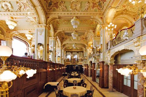 Café New York, Budapest  Zu den prunkvollsten Kaffeehäusern Budapests zählt das 1894 eröffnete Café New York. Zu Beginn der 1890er Jahre ließ die New York Life Insurance Company am Budapester Großen Ring ein aufwendiges Gebäude durch den Architekten Alajos Hauszmann errichten.   Das Café wurde schließlich im Jahr 1894 eröffnet und überdauerte Kriege und Regimewechsel weitestgehend unbeschadet bis heute. Es befindet sich im Erd- und Untergeschoss und ist mit üppigem Dekor ausgestattet, das stark an Kirchenräume erinnert.