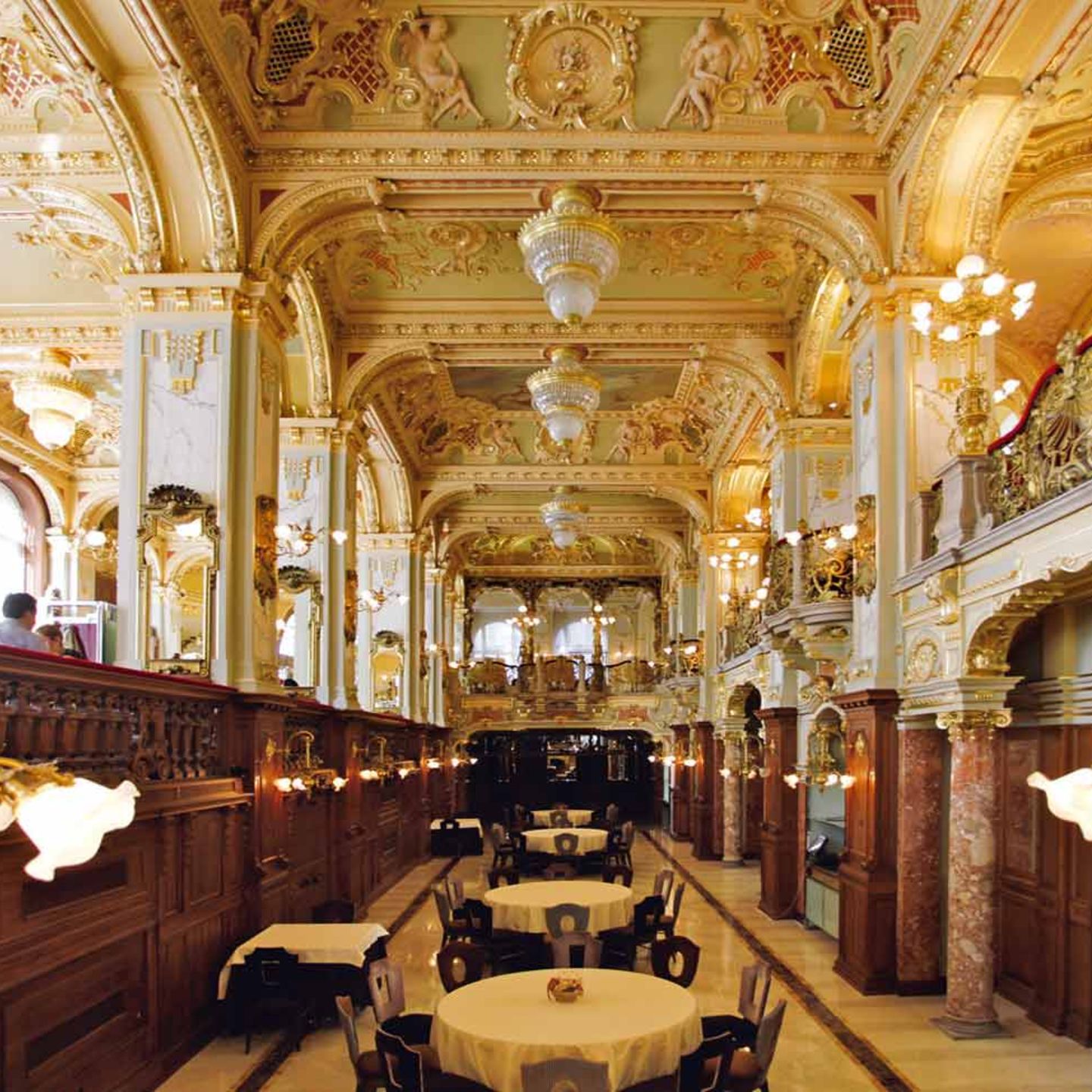 Café New York, Budapest  Zu den prunkvollsten Kaffeehäusern Budapests zählt das 1894 eröffnete Café New York. Zu Beginn der 1890er Jahre ließ die New York Life Insurance Company am Budapester Großen Ring ein aufwendiges Gebäude durch den Architekten Alajos Hauszmann errichten.   Das Café wurde schließlich im Jahr 1894 eröffnet und überdauerte Kriege und Regimewechsel weitestgehend unbeschadet bis heute. Es befindet sich im Erd- und Untergeschoss und ist mit üppigem Dekor ausgestattet, das stark an Kirchenräume erinnert.