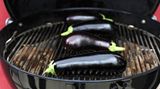 Ab auf den Grill. Die Auberginen liegen nicht direkt über den Kohlen, sondern dazwischen. Durch die indirekte Hitze beim geschlossenen Deckel können sie so in aller Ruhe vor sich hin garen.