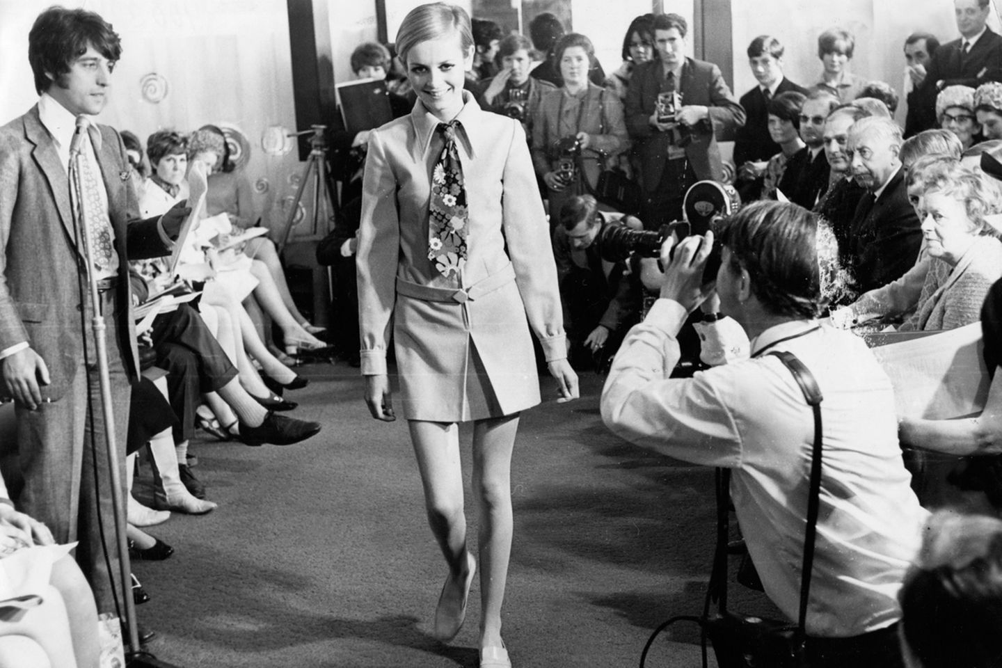 Es ist eher ungewöhnlich, dass ein Kleidungsstück nach dem Model benannt wird, das es präsentiert. In diesem Fall ist es anders: Bis heute ist der Schnitt als Twiggy-Kleid bekannt. Das Model präsentiert es mit einnem bunten Schlips.