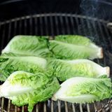 Die Temperatur über den Kohlen beträgt etwa 250 Grad, die flache Seite bekommt schnell ein leichtes Brandig, also geröstete Streifen vom Grillrost. Verbrennen sollte der Salat jedoch nicht, haben Sie also stets ein Auge drauf!