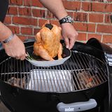 Frisch angemalt und mit Kräutern versehen kommt das Huhn samt Sitz auf den Grill. Die Holzkohlen liegen links und rechts, die Mitte bleibt frei.