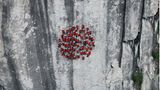 Rote Punkte bilden einen kreisrunden Farbklecks an der Felswand. Für diese Aufnahme reisten Bösch und seine Bergführer in den Süden der Schweiz, in den Tessin.