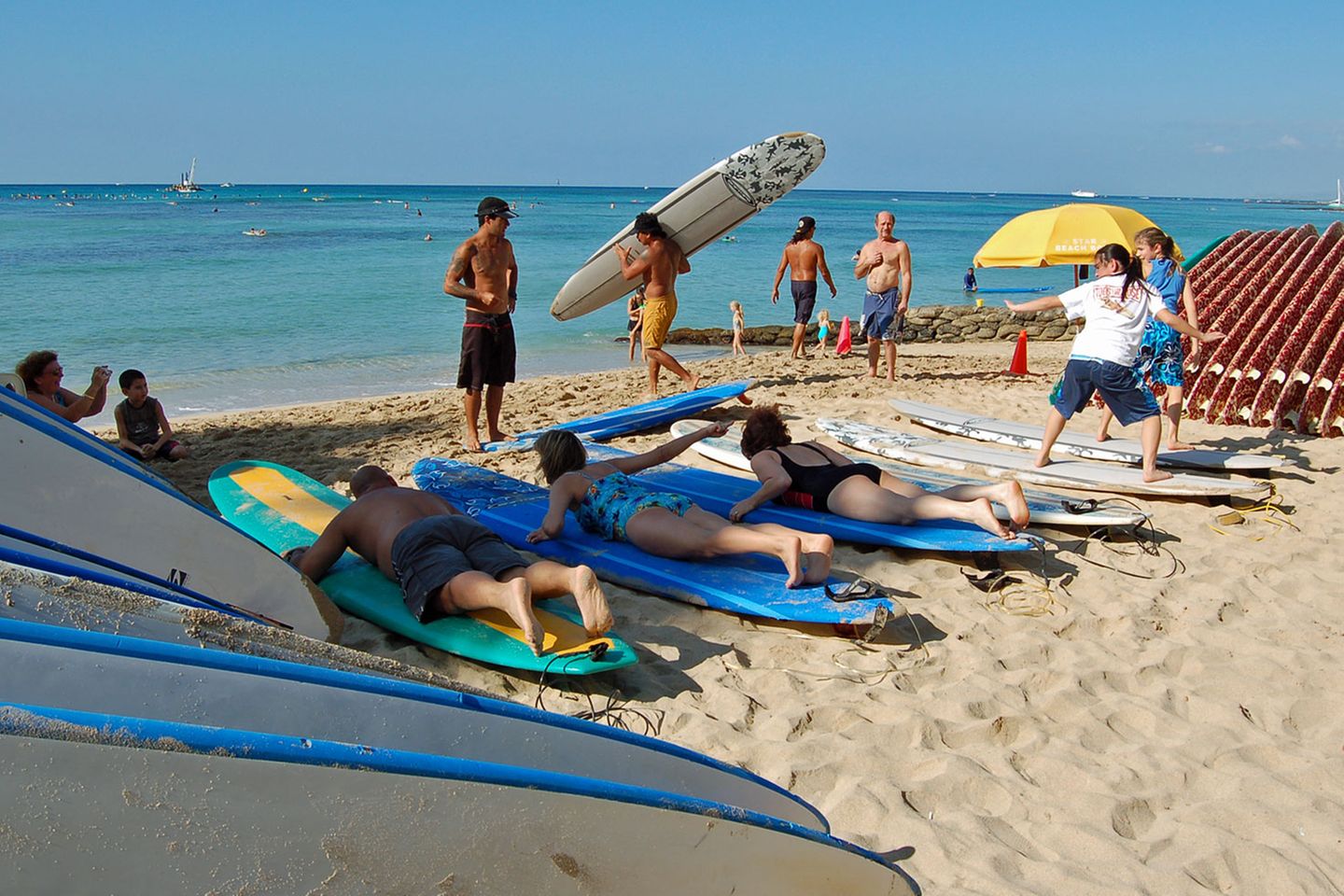 Hawaii-Inseln Oahu und Kauai: Trockenübungen an Land In Waikiki packt man nicht nur die Badehose ein, sondern nimmt statt des Sonnenschirms ein Surfboard mit zum Strand. Schon ein kurzer Tageskurs reicht, um später auf Wellen zu reiten. Die Kurse beginnen zunächst mit Trockenübungen auf festem Untergrund. Oft geben knackige Beachboys jungen Japanerinnen Surfunterricht. Trockenübungen an Land In Waikiki packt man nicht nur die Badehose ein, sondern nimmt statt des Sonnenschirms ein Surfboard mit zum Strand. Schon ein kurzer Tageskurs reicht, um später auf Wellen zu reiten. Die Kurse beginnen zunächst mit Trockenübungen auf festem Untergrund. Oft geben knackige Beachboys jungen Japanerinnen Surfunterricht.