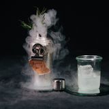 Remind Me  Gerade Alkohol ist für die Gedächtnisleistung nicht gerade förderlich und man vergisst die wichtigsten Dinge: die Namen der Gäste, die eigenen Cocktail-Rezepte und was nicht noch alles ... Ein bedachter Bartender sorgt da natürlich vor. Aus dem Nebel, der sich über die Erinnerung legt, ragt hier ein Drink mit Rosmarin, denn das soll angeblich gedächtnisfördernd wirken. Ausprobieren kann man die Sache ja mal, eine Anti-Filmriss-Garantie gibt es ab dem dritten Glas trotzdem nicht mehr ...  Zutaten:  50ml Rhum Agricole  20ml frisch gepresster Limettensaft  15ml Rosmarinsirup*  Trockeneis  Trinkgefäß: Weckglas  Zubereitung:  Alle Zutaten, abgesehen vom Trockeneis, in einen kleinen Shaker geben, mit Eis auffüllen und schütteln. Anschließend einen Chunk Trockeneis in den Shaker geben. Shaker verschließen und die obere Kappe des Shakers öffnen, sodass Dampf austritt. Servieren Sie separat zu dem Shaker ein mit Eis gefülltes Weckglas. Bei der Arbeit mit Trockeneis unbedingt Schutzkleidung tragen und die allgemeinen Vorsichtsmaßnahmen befolgen!  *500g Zucker, 300ml Wasser und 8 Zweige frischen Rosmarin in einen Vakuumbeutel geben, verschließen und bei 65°C für 55 Minuten ins Wasserbad legen. Nach Ablauf der Zeit den Sirup passieren, sodass keine Festbestandteile in der Flüssigkeit verbleiben.