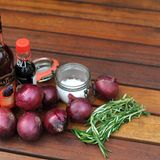 Geröstete Rosmarin-Zwiebeln  4 große, gelbe und rote Zwiebeln 2 EL Rotwein-Essig 2 EL Olivenöl Salz schwarzer Pfeffer 1 TL frischer, geschnittener Rosmarin 2 EL Olivenöl zum Beträufeln 100 ml Sojasoße 50 g Brauner Zucker