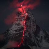 Auf dem nächtlichen Hörnligrat, der Route der Erstbegeher am Matterhorn, hat Bösch zusammen mit Zermattern Bergführern Alpinisten mit roten Stirnlampen positioniert, deren Schein die Wolkenfetzen am Gipfel zum Leuchten bringt.