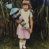 Swantje Dake, Teamleiterin Nachrichten, 1984 in Uslar  Weiße Kniestrümpfe, die aussahen wie selbst gehäkelt. Waren sie aber nicht. Sie rutschten, aber ich liebte sie. Natürlich musste ich sie am Einschulungstag tragen. Und die Lieblingssandalen auch, die weinroten. Dazu der rosa-blaue Rock.   Meine Schultüte glänzte blau-metallic in der Sonne. Sie war schwer, weil gut gefüllt. Mit was, kann ich heute nicht mehr sagen. Ich erinnere mich noch an die Verkehrsschilder, die darauf waren. Eher so ein Jungs-Ding. Aber rosa und Pferde waren nicht meins. Auf eine andere Schultüte waren wir alle neidisch: Katjas Tüte war so prall gefüllt, dass sie kaum zugeknotet werden konnte. Was drin war, war uns egal. Es sah nach viel aus. Aber Katja lächelt auf keinem Foto. Vermutlich war die Bürde einfach zu groß.