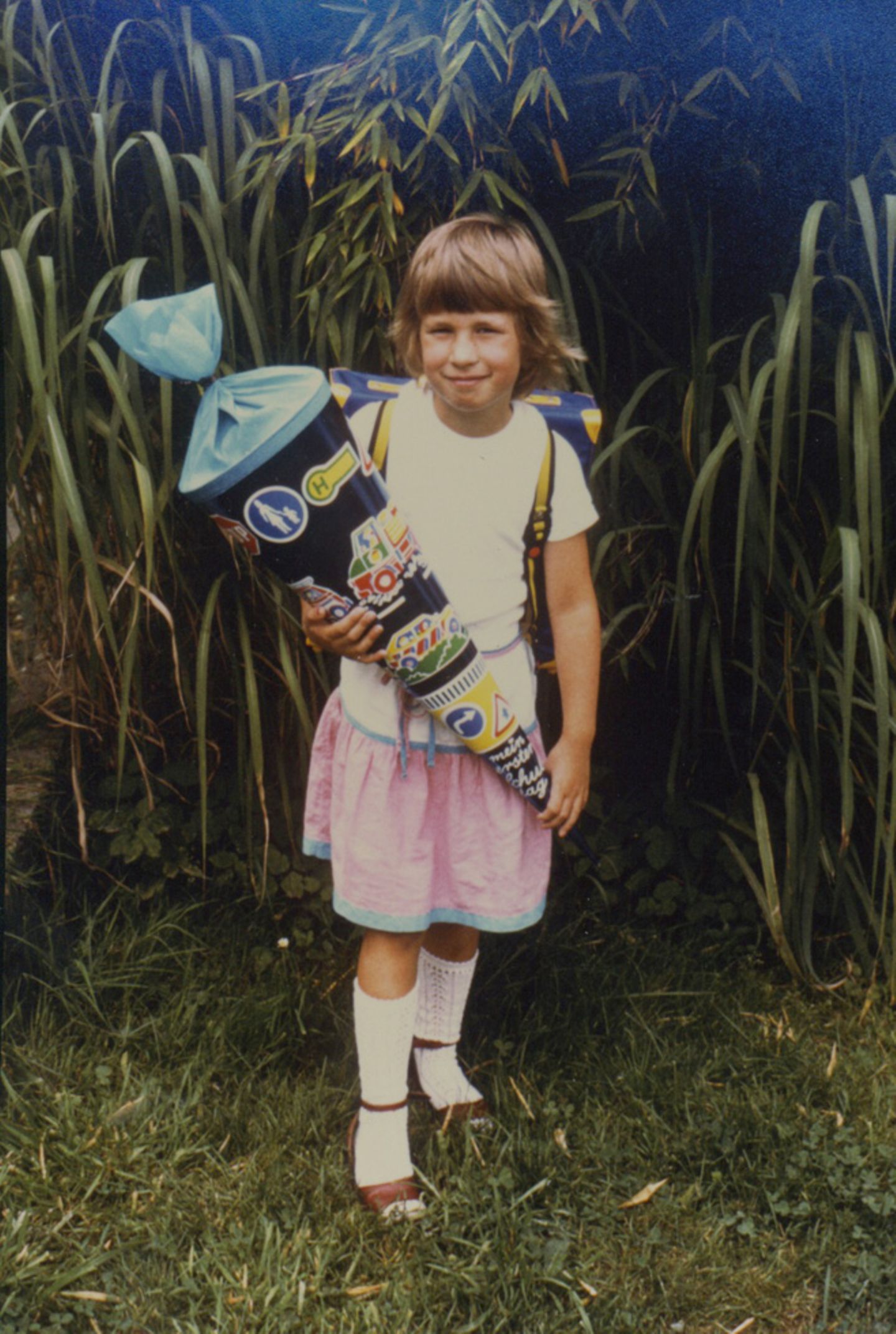 Einschulung durch die Jahrzehnte: Swantje Dake, Teamleiterin Nachrichten, 1984 in Uslar Weiße Kniestrümpfe, die aussahen wie selbst gehäkelt. Waren sie aber nicht. Sie rutschten, aber ich liebte sie. Natürlich musste ich sie am Einschulungstag tragen. Und die Lieblingssandalen auch, die weinroten. Dazu der rosa-blaue Rock. Meine Schultüte glänzte blau-metallic in der Sonne. Sie war schwer, weil gut gefüllt. Mit was, kann ich heute nicht mehr sagen. Ich erinnere mich noch an die Verkehrsschilder, die darauf waren. Eher so ein Jungs-Ding. Aber rosa und Pferde waren nicht meins. Auf eine andere Schultüte waren wir alle neidisch: Katjas Tüte war so prall gefüllt, dass sie kaum zugeknotet werden konnte. Was drin war, war uns egal. Es sah nach viel aus. Aber Katja lächelt auf keinem Foto. Vermutlich war die Bürde einfach zu groß. Swantje Dake, Teamleiterin Nachrichten, 1984 in Uslar Weiße Kniestrümpfe, die aussahen wie selbst gehäkelt. Waren sie aber nicht. Sie rutschten, aber ich liebte sie. Natürlich musste ich sie am Einschulungstag tragen. Und die Lieblingssandalen auch, die weinroten. Dazu der rosa-blaue Rock. Meine Schultüte glänzte blau-metallic in der Sonne. Sie war schwer, weil gut gefüllt. Mit was, kann ich heute nicht mehr sagen. Ich erinnere mich noch an die Verkehrsschilder, die darauf waren. Eher so ein Jungs-Ding. Aber rosa und Pferde waren nicht meins. Auf eine andere Schultüte waren wir alle neidisch: Katjas Tüte war so prall gefüllt, dass sie kaum zugeknotet werden konnte. Was drin war, war uns egal. Es sah nach viel aus. Aber Katja lächelt auf keinem Foto. Vermutlich war die Bürde einfach zu groß.